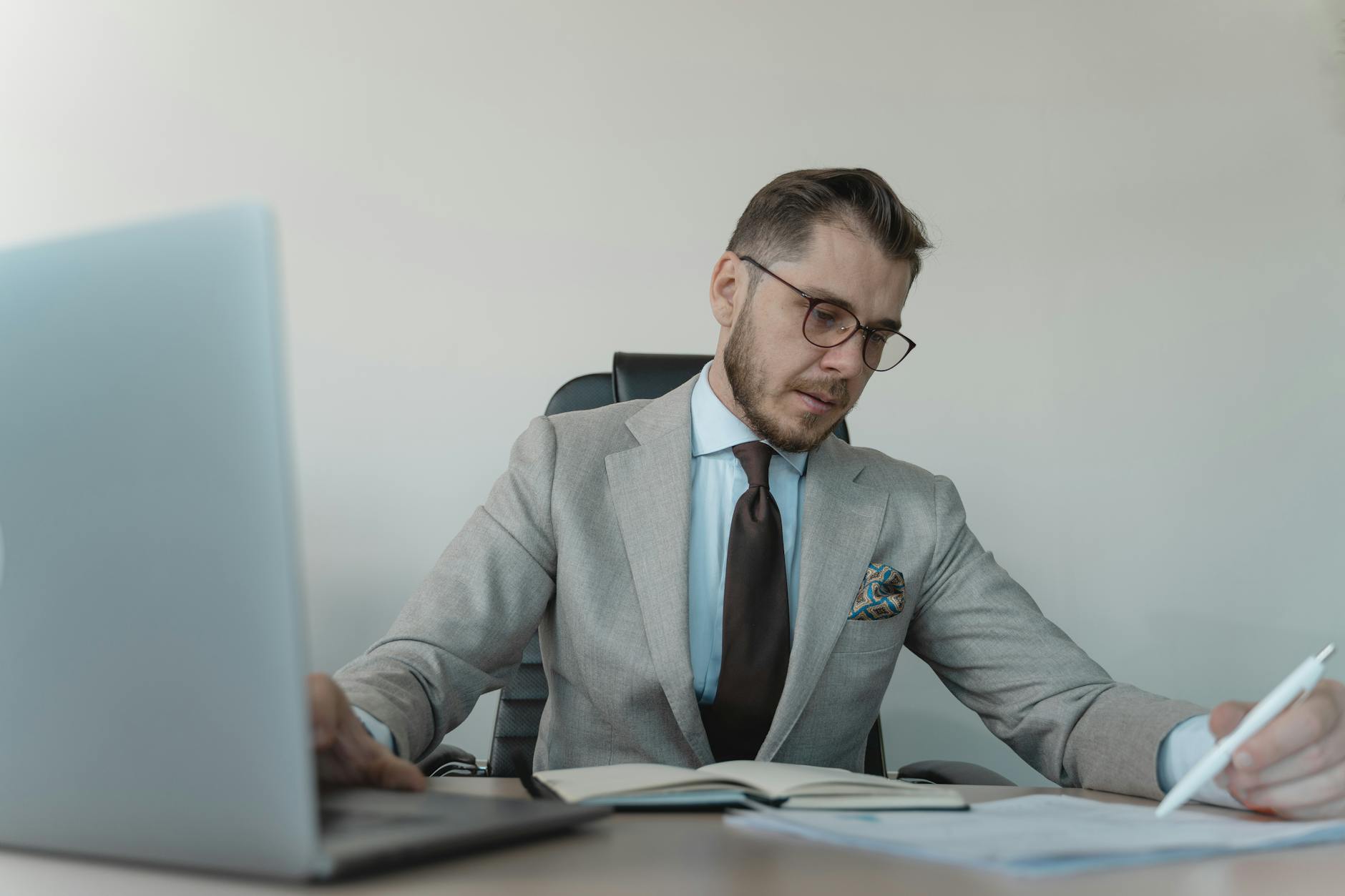 man in gray suit jacket working on a laptop